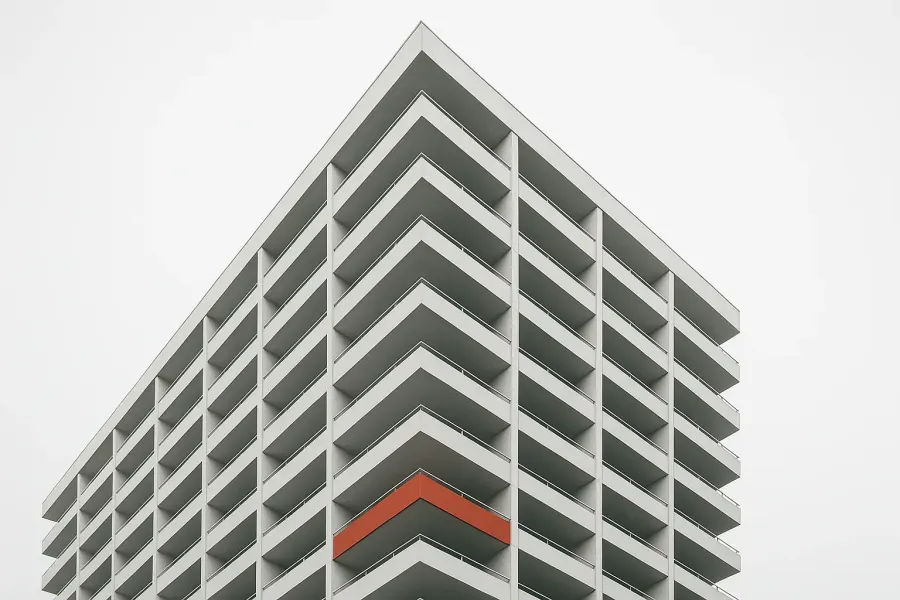 White modernist residential tower with a single vermilion balcony